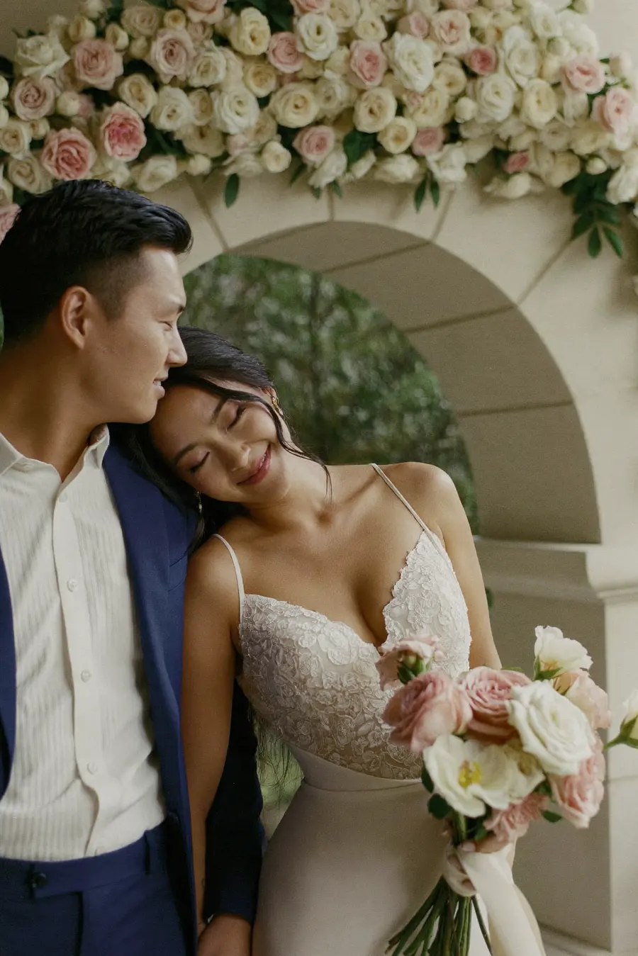 Claire and Daniel under a stone arch dressed with roses